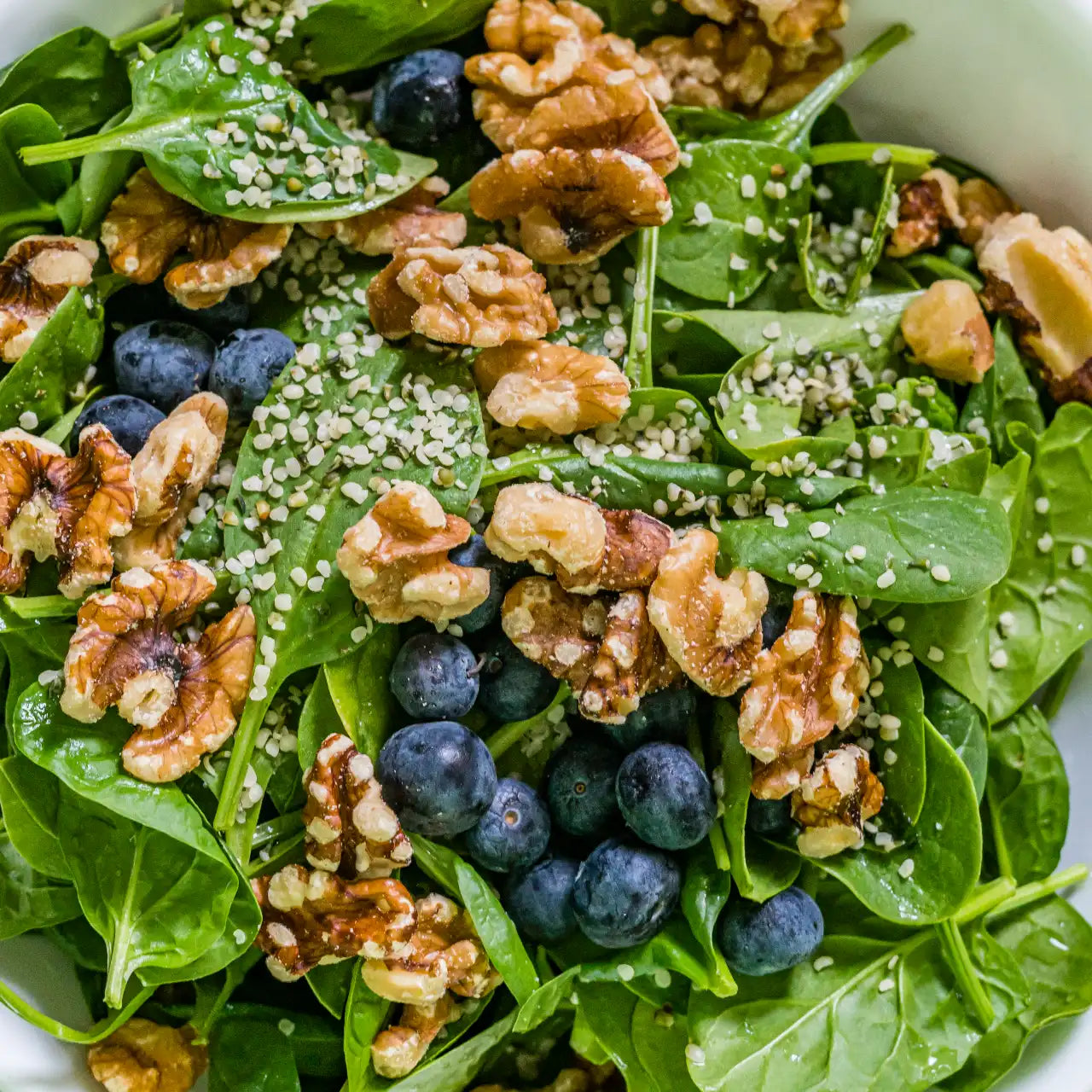 A Spinach, Blueberry and Walnut Salad in a white bowl